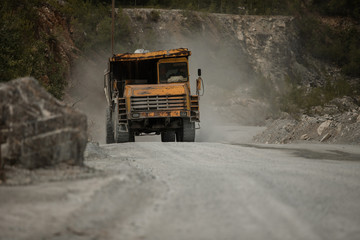 Fototapeta na wymiar yellow truck. loaded with coal. sunny weather. kamaz bears a white breed. coal mine. extract cement 