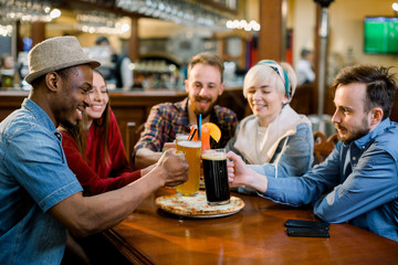 A company of five young people having fun, eating pizza, drinking drinks, cocktails, juices in a cafe. Meeting best friends