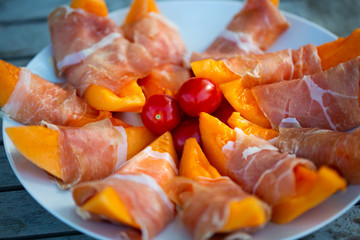 Melon with parma ham on garden table
