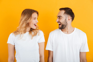 Portrait of adorable young couple man and woman in basic t-shirts smiling and looking at each other