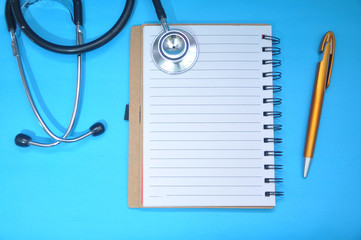 Blank notebook and medical stethoscope top view. Doctor’s work table concept. Health care concept