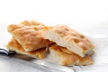 slices of traditional italian focaccia and a knife rest on a marble table with copy space for your text