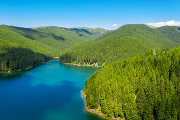 Fototapeta na wymiar Mountain forest lake landscape. Aerial view. View on the turquoise color lake between mountain forest. Over beautiful turquoise mountain lake and green forest. National park. Green pine and fir trees