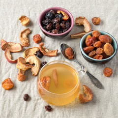 A small glass mug with compote and a mixture of dried fruit on a linen tablecloth. Selective focus.