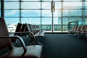 Passenger seats in departure lounge at airport terminal. Interior of airport terminal. Chairs in departure area at international gate. Transport business and travel. Empty seat for waiting flight.