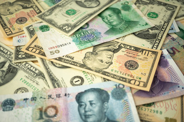US dollar stack and Chinese yuan banknotes on the table The concept of a trade war between the United States and China