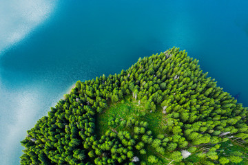 Aerial view of a forest lake. Aerial view of blue lake and green forests on a sunny summer day. Drone photography. Forest and lake border, Toned image from above. Coastline view from the drone.