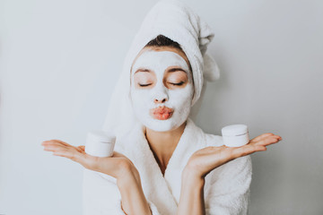 woman has fun with a facial mask.Beautiful woman with a clay or a mud mask on her face over white...