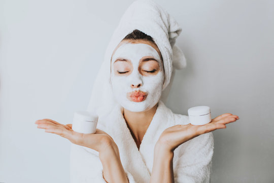 woman has fun with a facial mask.Beautiful woman with a clay or a mud mask on her face over white background. cream on her face, mask on the face, a towel on his head, problem skin
