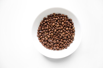 coffee beans brown closeup with blurred background in white plate on white isolated background