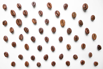 different varieties of coffee brown beans on a white isolated blurred background laid out in a staggered manner