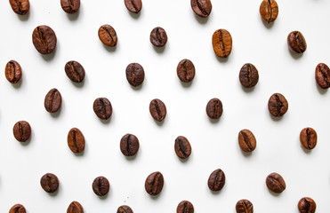 different varieties of coffee brown beans on a white isolated blurred background laid out in a staggered manner