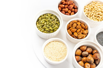 Various Nuts and Seeds on White Background in the Bowls with Free Space for Text