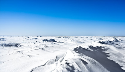 Snow desert view on Kola Peninsula; clear blue sky, snow dunes formed by strong northen winds;