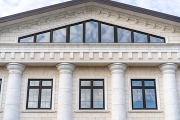 Beautiful window in a classic building with white walls. In the glass reflection of the sky with clouds. view from the facade.