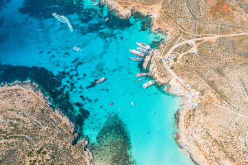 Aerial view famous Blue Lagoon in the Mediterranean Sea. Comino Island, Malta. Beach and vacationers, a bay pier with ships and boats.