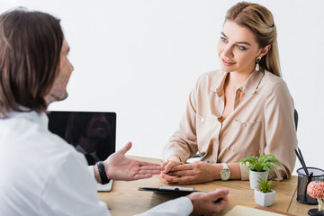 Obraz premium doctor talking with patient, holding document in hands and sitting behind wooden table