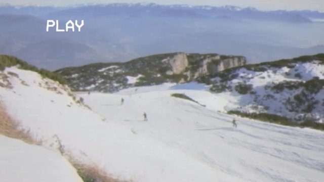A VHS retro fake shot: experienced skiers and snowboarders starting a descent from a ski slope (outdoor mountain sport activities).