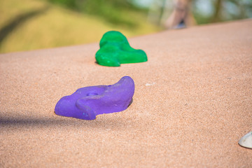 Fototapeta na wymiar Stones-hooks for children's climbing wall. Children's park in the fresh air. Closeup