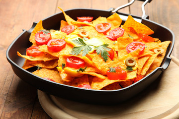 Corn chips nachos with cherry and olives in cheese sauce