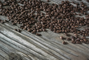 A roasted, fragrant coffee beans lie on the old wooden textured table. Copy space below