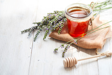 Jar of liquid honey with lavender on white wooden table 