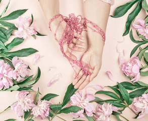 hands of a young girl with smooth skin and a bouquet of pink peonies