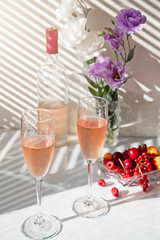 bottle and glasses of pink wine flowers and fruit
