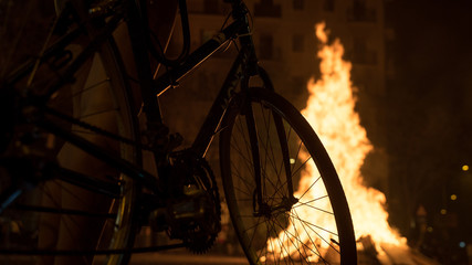 Bicicle wheel. People watching big fire. Yellow flames rising up. Night of saint Joan in Barcelona. Fireworks and hot fire. 