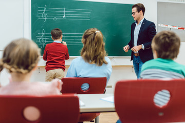 Student working with teacher at the board in front of class