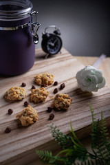 Fototapeta premium A chocolate chips cookies with jar, flower and retro clock as background