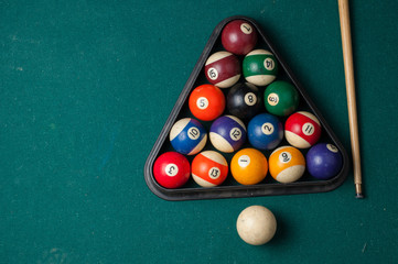 Old billiard balls and stick on a green table. billiard balls isolated on a green background.
