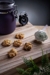 A chocolate chips cookies with jar, flower and retro clock as background