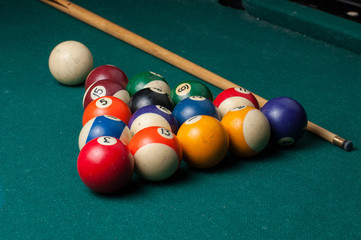 Old billiard balls and stick on a green table. billiard balls isolated on a green background.