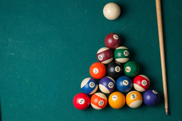 Old billiard balls and stick on a green table. billiard balls isolated on a green background.