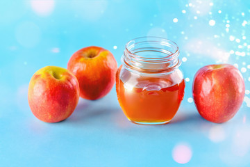 Rosh hashanah jewish holiday concept. Apples and honey jar for jewish new year holiday over blue background. Healthy food.Bokeh lights.