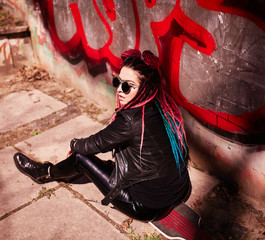 Beautiful young girl with colored dreads sitting in the sun