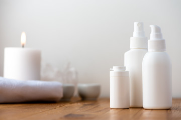 White plastic cosmetic bottles on a wooden table, selective focus. Spa concept, skincare cosmetic products