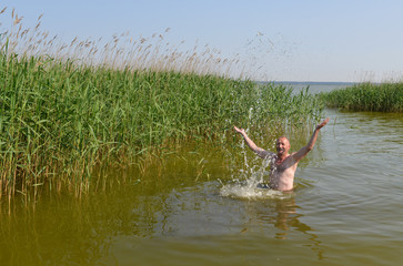 Mann badet im Schilfgewässer
