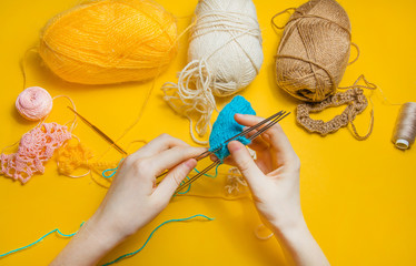 Woman knits woolen clothes. Knitting needles. a ball of thread. natural wool. Girls ' hands. Isolated on yellow background. the concept of the work.