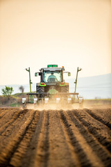 Farmer seeding, sowing crops at field. Sowing is the process of planting seeds in the ground as part of the early spring time agricultural activities. © oticki