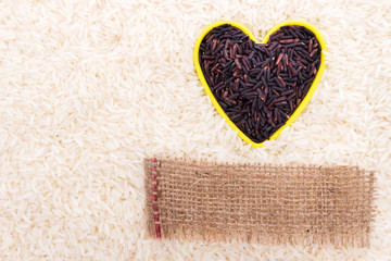 Heart shape of rice berry grains on white rice background with blank label of natural sackcloth: protects heart health and being good for the kidney, stomach and liver