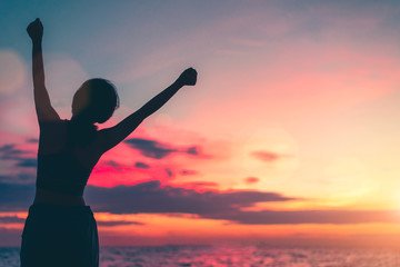 Happy woman standing arms outstretched back and enjoy life on the beach at Sea, background sky sunset silhouette.