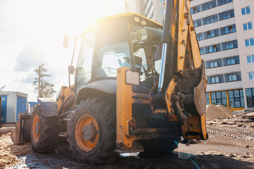 Wheel loader excavator or bulldozer on construction site of new building in sunlight