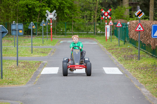 Adorable Young Boy On A Go Cart Driving In A Traffic Learning Parcours In An Amusement Park 