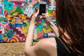 woman taking picture of colourful wall with mobile phone