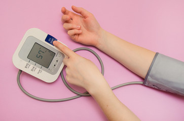 Measurement of pressure. The woman takes care of her health by checking her blood pressure and pulse on her arm. lilac background
