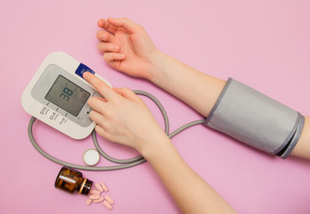 Measurement of pressure. The woman takes care of her health by checking her blood pressure and pulse on her arm. lilac background