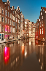 Fototapeta premium Canal between buildings at night in Amsterdam