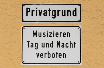 Fototapeta na wymiar Signs at a city house in the german city Munich. Translation: private land, music making prohibited day and night.